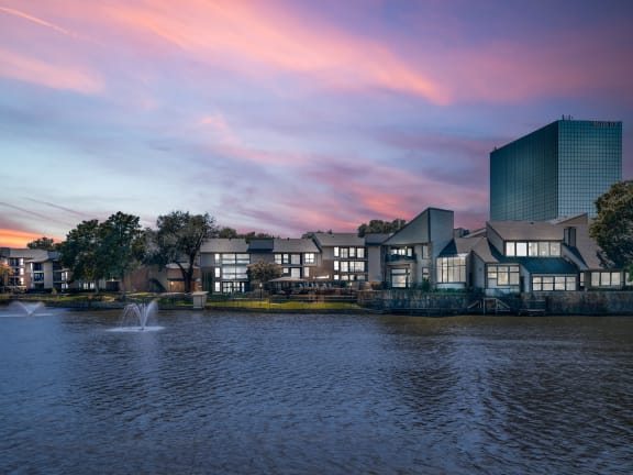 a sunset over a lake with buildings in the background at Lakeside Apartments, Texas, 75231